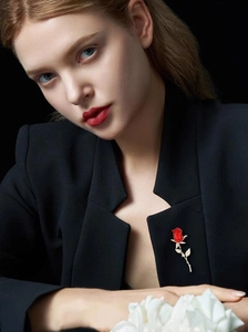 Détail de la broche rose rouge avec tige dorée sur revers noir pour un style élégant