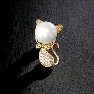 Close-up of golden cat brooch with pearl head and sparkling zircon stone detailing