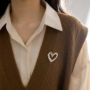 Broche cœur élégante dorée avec perles portée sur un gilet vintage et chemise