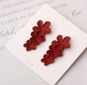 Dettaglio di orecchini a triplo fiore rosso con finitura opaca e perni in argento 925
