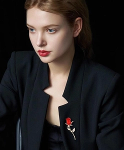 Élégante broche rose rouge avec tige dorée sur le revers d'un tailleur noir chic