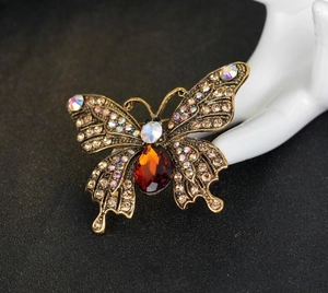 Detailansicht der Retro Schmetterlingsbrosche mit orangefarbenem Stein und Strass