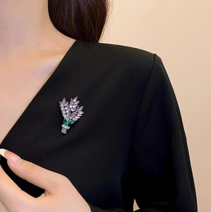 Exquise broche lavande avec pierres violettes et accents verts sur un blazer noir