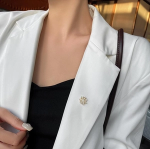 Détail d'une broche marguerite en œil de chat avec strass sur le revers d'un tailleur