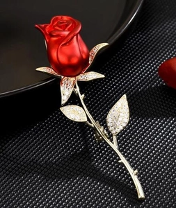 Détail d'une broche rose rouge élégante avec tige dorée et cristaux pavés étincelants