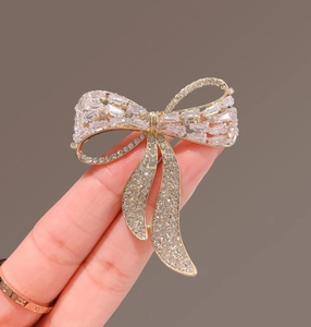 Close-up of luxury bow brooch with sparkling zircon crystals and golden metal base