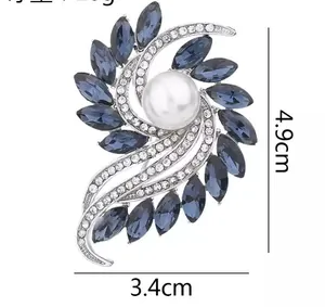 Detail of silver floral brooch with blue marquise crystals and a large white pearl center