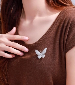Detail of vintage butterfly brooch with pavé zircon stones on a brown knitted sweater