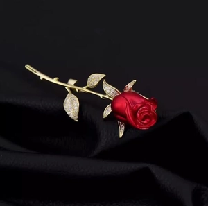 Vue macro d'une élégante broche rose rouge avec détails dorés et zircons sur cuir noir
