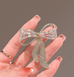 Detail of a luxury gold bow brooch featuring sparkling zircon inlay and elegant tassels