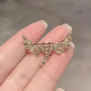 Elegante spilla a cuore con ali d'angelo dorate con ciondolo a nappa e cristalli scintillanti