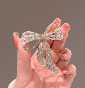 Close-up of gold bow brooch with micro-paved crystals on dark background