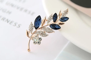 Close-up of elegant leaf brooch with navy blue crystals and rose gold metal plating
