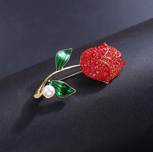 Spilla rosa di lusso con strass rossi, smalto verde e perla su uno sfondo nero raffinato