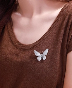 Macro shot of micro-paved cubic zirconia butterfly brooch on a brown knit sweater