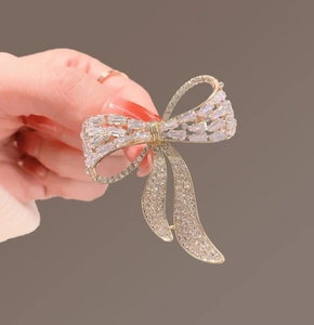 Macro detail of luxury bow brooch with clear zircon pavé on gold-tone metal plating