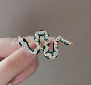 Detail of green enamel snake brooch with sparkling crystals and gold-plated finish