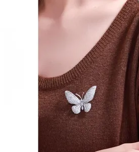 Detailed view of silver butterfly brooch with micro-paved cubic zirconia on brown sweater