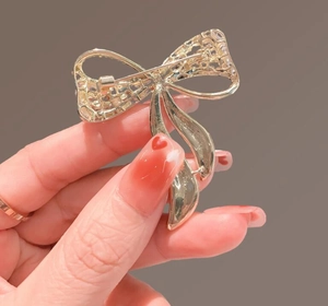 Detail of the golden bow brooch back showing fine mesh texture and secure safety pin clasp