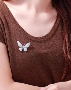 Macro detail of micro-pave butterfly brooch pinned on brown knit sweater with sparkling zircons