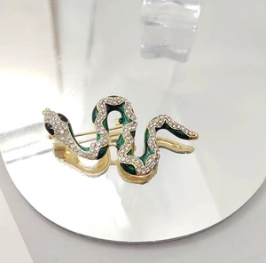 Macro shot of green enamel snake brooch with sparkling diamonds on gold plating