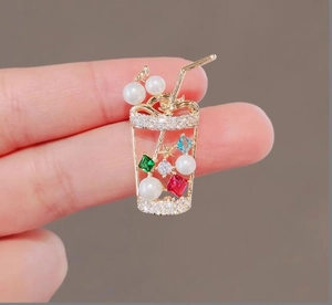 Macro detail of drink cup brooch with colorful zircons, pearls and sparkling crystals