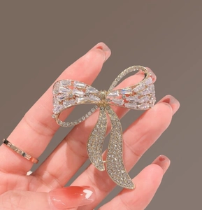 Detail of hand-held gold bow brooch featuring sparkling crystals and clear rhinestones