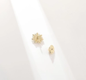Détail de la broche fleur dorée avec son fermoir papillon sur un fond blanc épuré