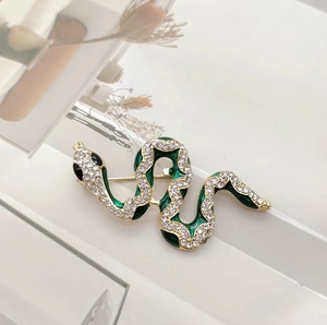 Macro detail of emerald green enamel snake brooch with sparkling pavé crystals