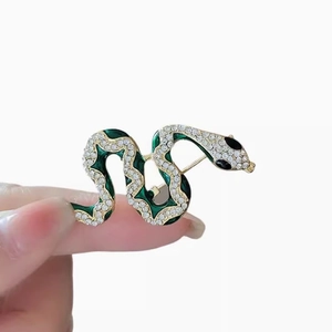 Sparkling crystal snake brooch with green enamel and gold plating in S-shape design