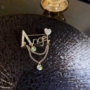 Détail de la broche dorée Angel avec strass, cœur et doubles chaînes pendantes