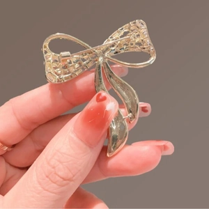 Elegant gold bow brooch in hollow weave design shown from the back with secure safety pin