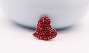 Détail d'une broche en forme de cœur avec strass rouges et base en métal argenté