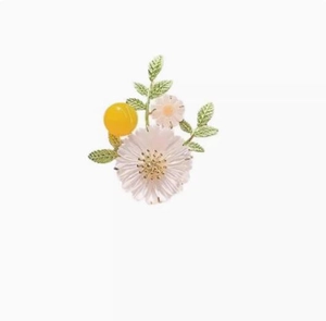 Macro detail of white and pink daisy brooch with green leaves and golden stamen