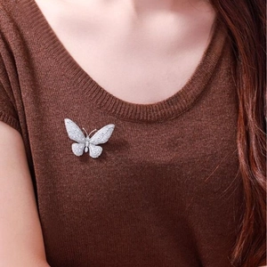Elegant vintage butterfly brooch with sparkling zircons pinned on a brown knit sweater