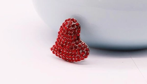 Macro d'une broche cœur en argent ornée de strass rouges éclatants sertis sur métal