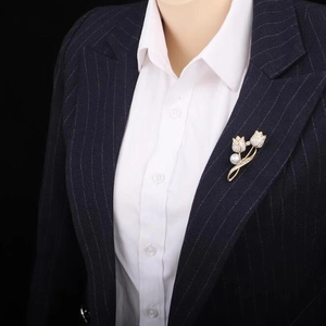 Détail d'une broche tulipe élégante avec cristaux blancs et perle sur un costume bleu