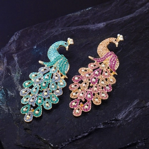 Exquisite peacock brooches with vibrant blue and pink rhinestones on a dark textured background