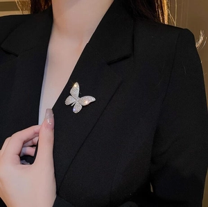 Close-up of a sparkling butterfly brooch with white rhinestones on a black suit lapel