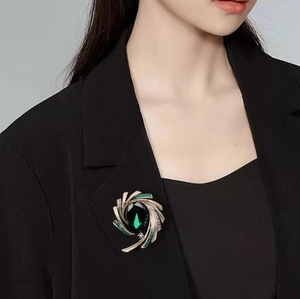 Detail of elegant crescent brooch with green gemstones on a black professional suit blazer