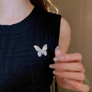 Detailed close-up of a sparkling butterfly brooch on a black knitted vest for women