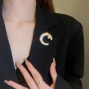 Vue détaillée d'une broche lune avec perle et zircons sur le revers d'un tailleur noir chic