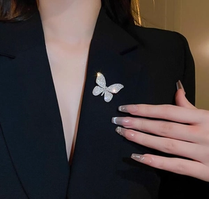 Detailed view of a sparkling butterfly brooch with white crystals on a black suit lapel