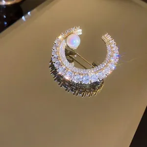 Broche croissant de lune argentée avec cristaux brillants et perle centrale blanche