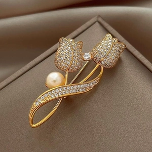 Élégante broche tulipe dorée avec zircons et perle sur un fond en soie luxueux
