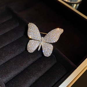 Elegant gold butterfly brooch with shimmering white crystals on a black jewelry box