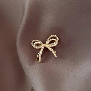 Primer plano del elegante broche de lazo dorado champán con perlas blancas y cristales