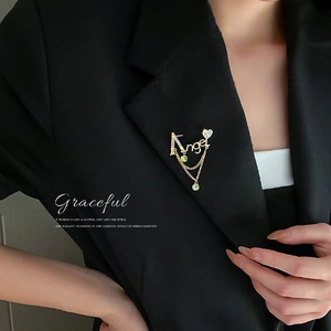 Broche lettre A dorée élégante avec pampilles vertes sur une veste de costume