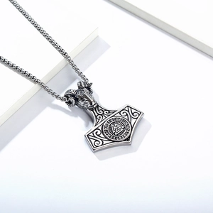 Macro shot of Viking ram head and Thor's hammer pendant with runes and Valknut symbol