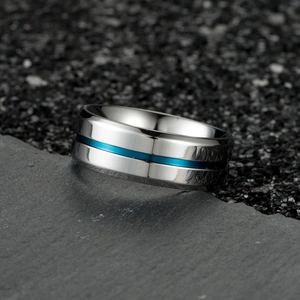 Polished stainless steel men's ring with blue grooved center on dark slate background